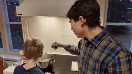 Pietari rakennuskerhossa kynttilöitä valamassa pienen kerholaisen kanssa