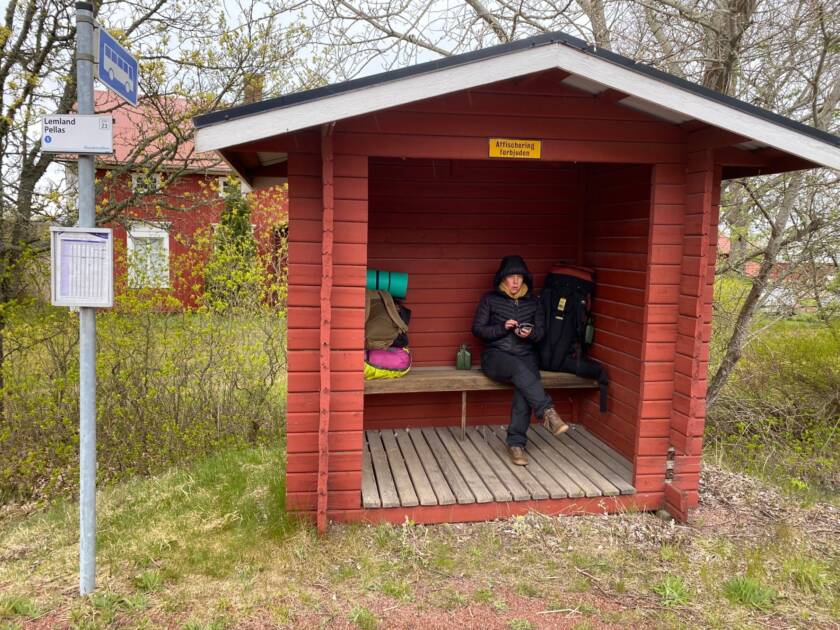 Vaeltaja bussipysäkkikatoksessa sateelta suojassa